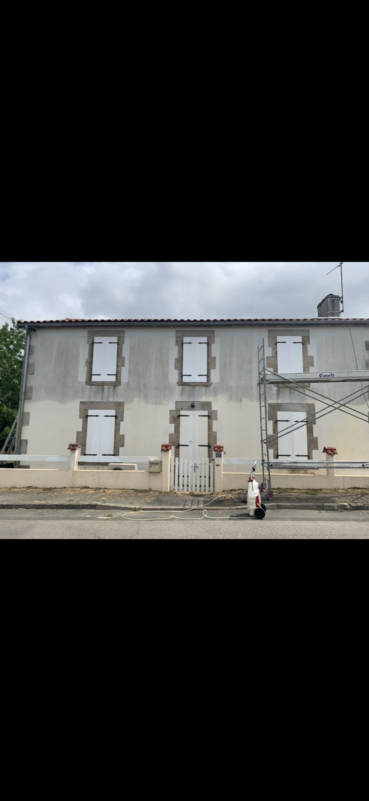 Nettoyage en cours d'une façade de maison en pierre enduite en Deux-Sèvres